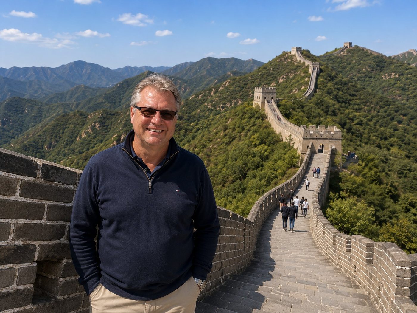 Radim Kaufmann on a restored section of the Great Wall of China, with stone watchtowers and a long zigzag of ramparts ascending forested ridges in the distance