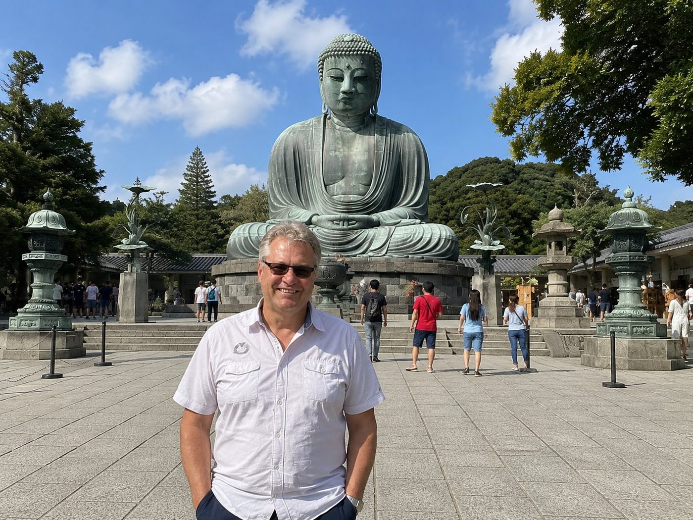 Radim Kaufmann standing before the Great Buddha of Kamakura at Kōtoku-in Temple, with the seated bronze Amida Buddha and lotus-shaped bronze lanterns behind him