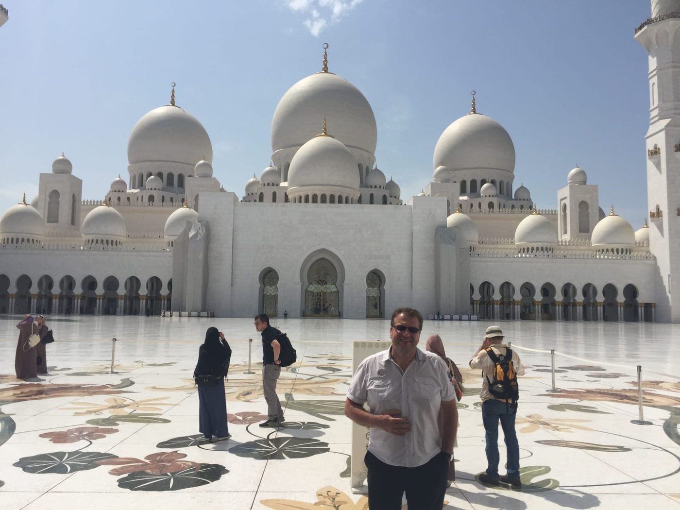 Radim Kaufmann at the courtyard of the Sheikh Zayed Grand Mosque in Abu Dhabi, with white marble domes and arches in the background